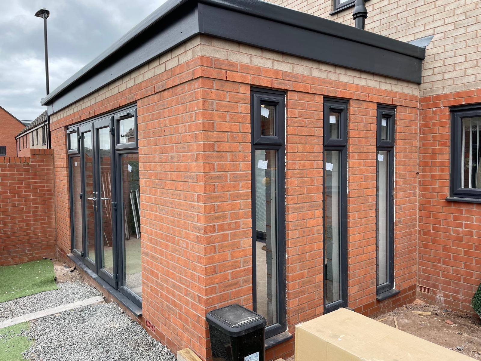 Completed single storey brick house extension with dark-framed glazing in Cannock