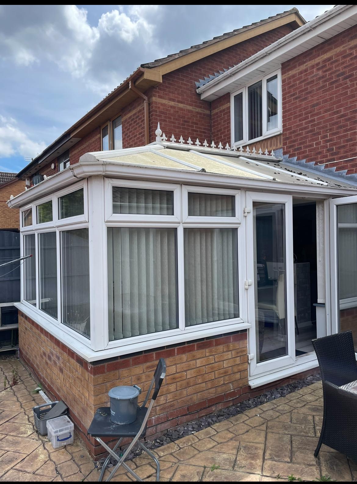Dated white uPVC conservatory with a polycarbonate roof on a red brick house before the upgrade