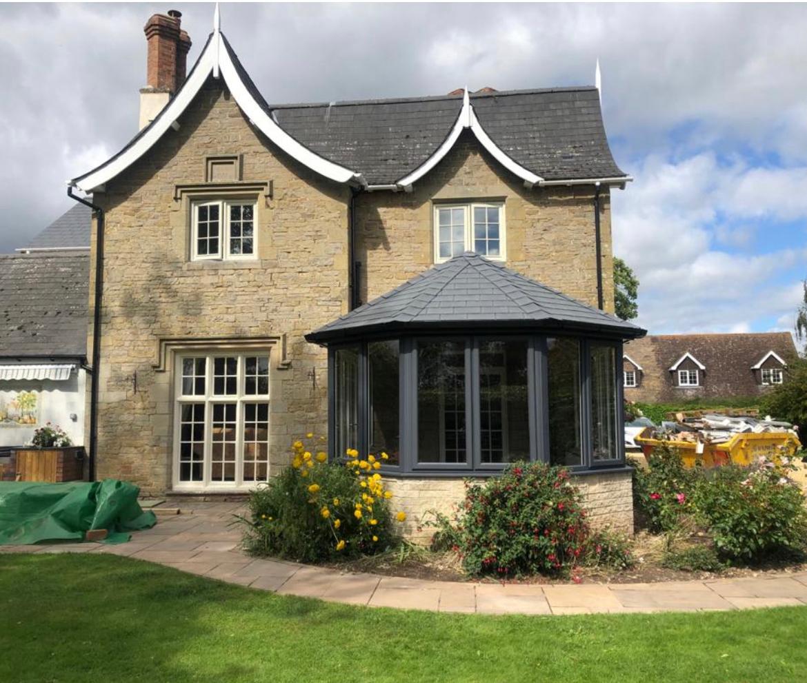 Replacement conservatory with anthracite grey frames and a solid tiled roof on the same stone cottage