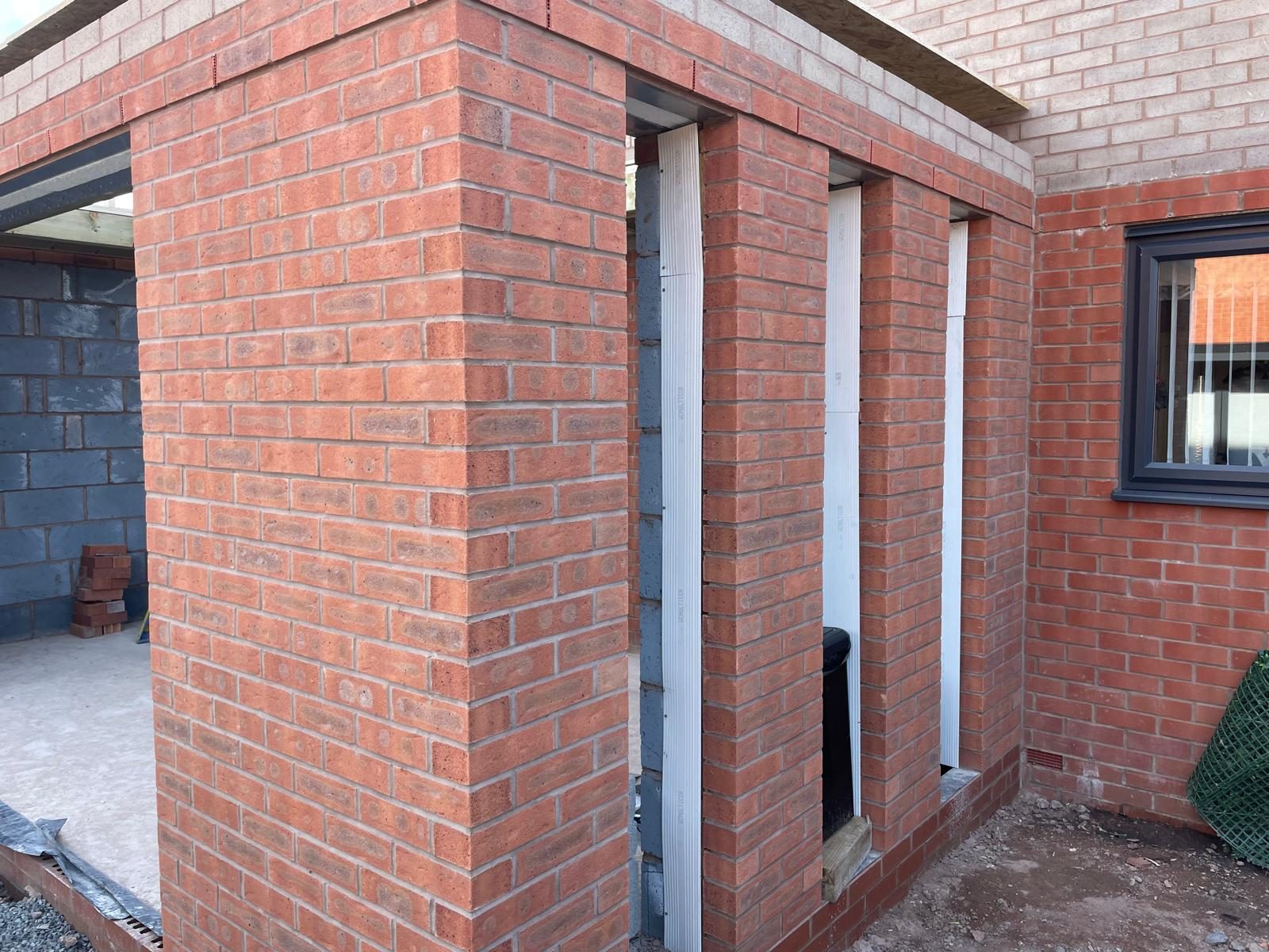 Brick orangery walls with tall window openings during construction in Cannock
