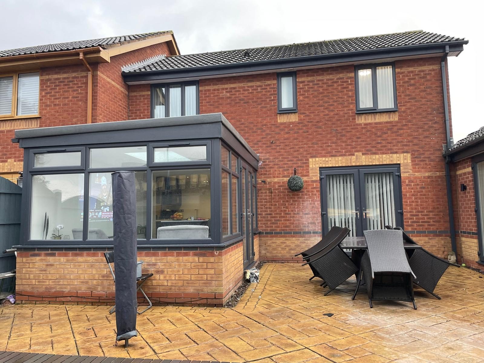 Dark-framed glazed garden room built onto a red-brick house in Cannock