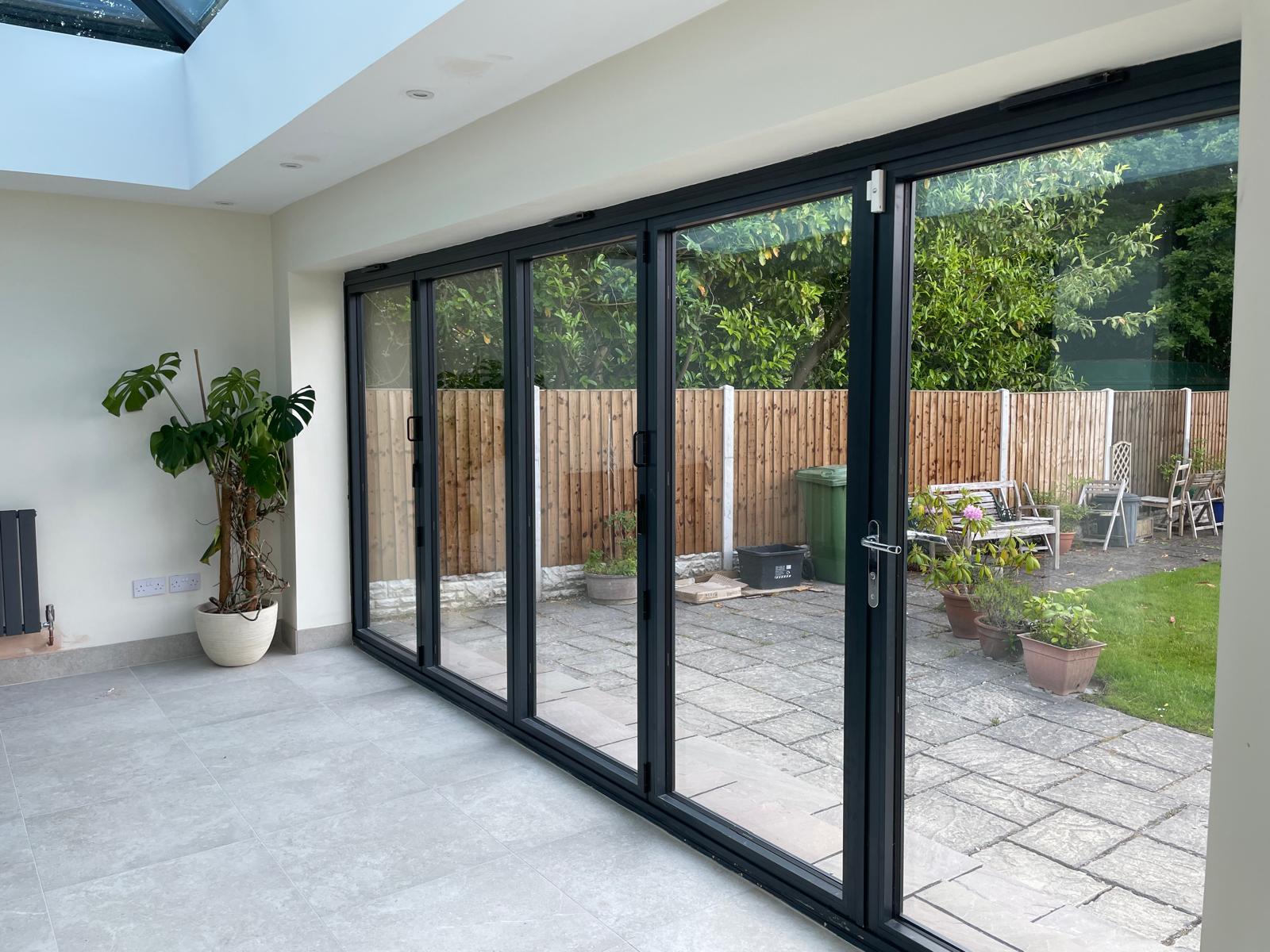 Orangery interior with anthracite bi-fold doors and roof lantern looking out to the garden
