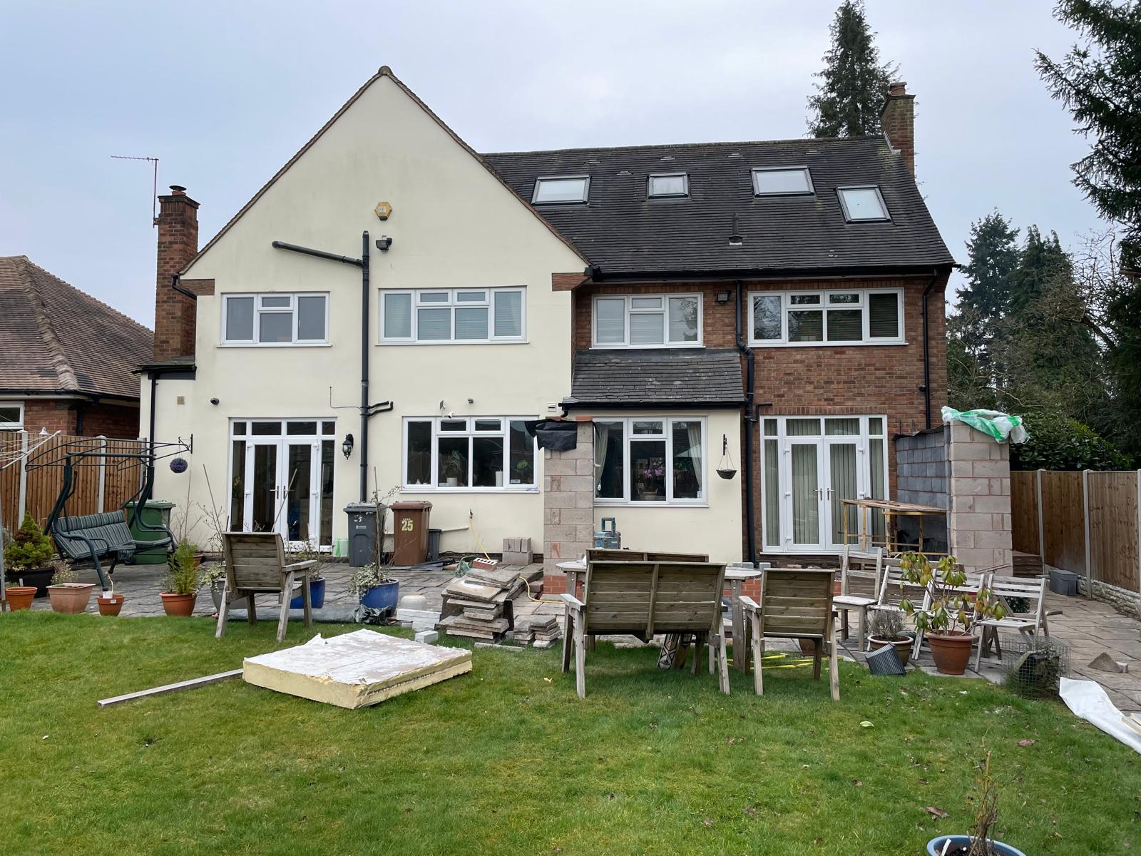 Rear of a rendered detached house before work, with the patio cleared ready for a single storey extension