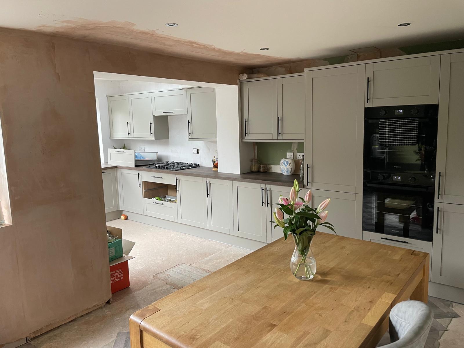 Newly fitted shaker kitchen with pale grey cabinetry, built-in ovens and a structural opening through to the hob run