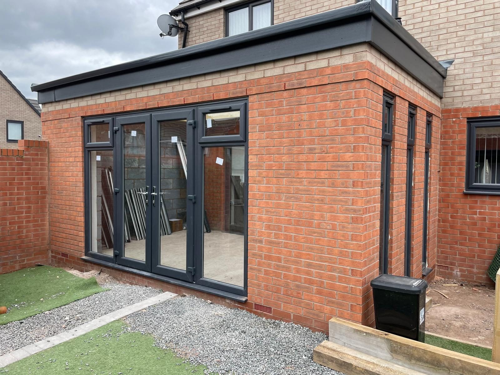 Completed single storey rear extension in matching red brick with grey French doors and a flat roof
