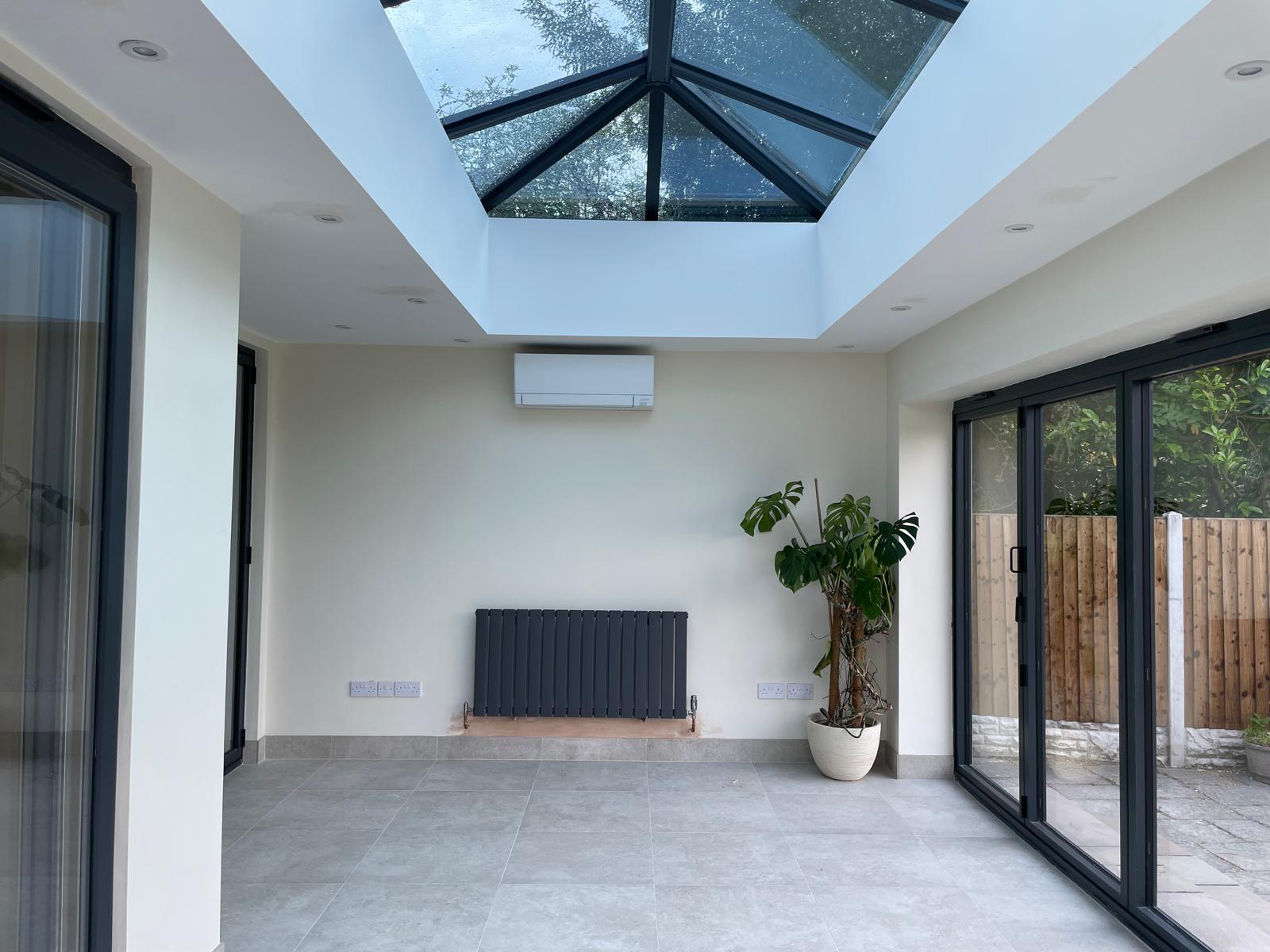 Completed orangery interior with a glazed roof lantern, anthracite radiator and tiled floor